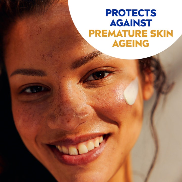 NIVEA Sun UV Face Shine Control Cream SPF50 50 ml motvirker aldringstegn på smilende kvinne med hvit krem på kinnet