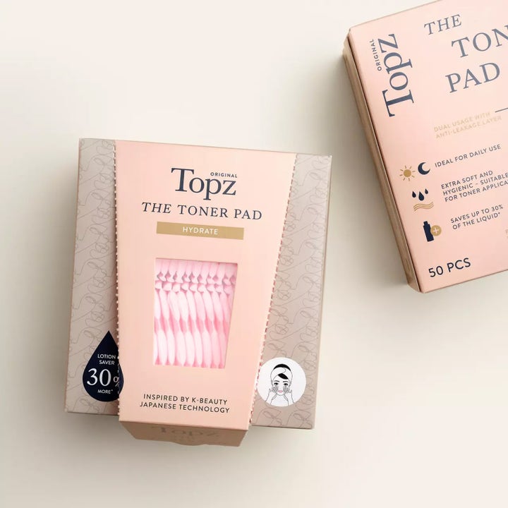 Topz Premium The Toner Pad 50 stk fuktighetsgivende hudpleieverktøy i lys rosa eske med vindu som viser padsene.