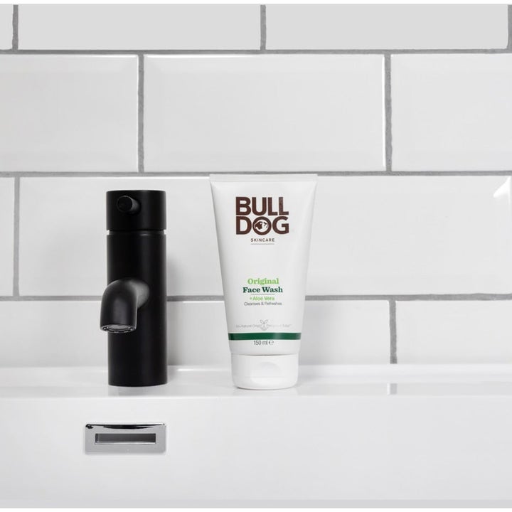 Bulldog Original Face Wash 150 ml rensende ansiktsvask i hvit tube ved siden av en moderne sort kran