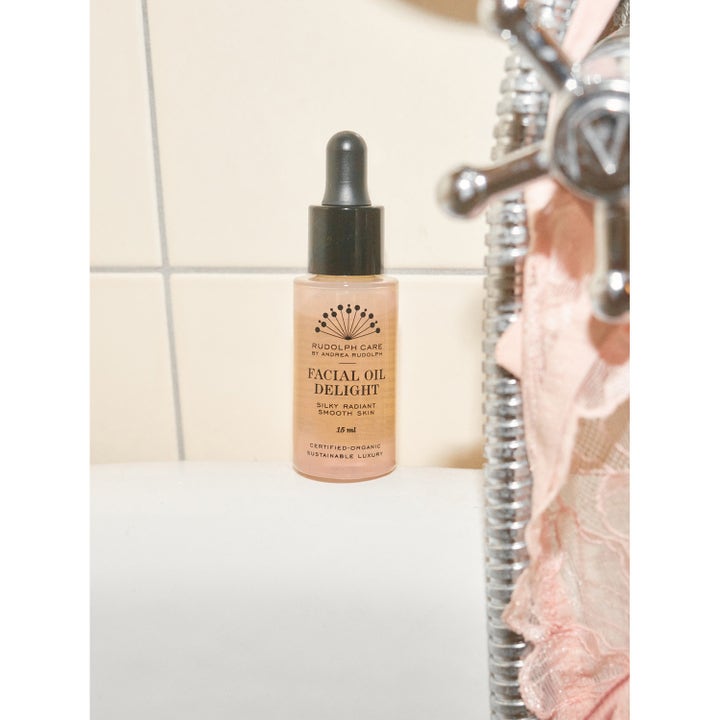 Rudolph Care Facial Oil Delight 15 ml ansiktsolje gir glød i liten glassflaske med sort pipette ved badekaret