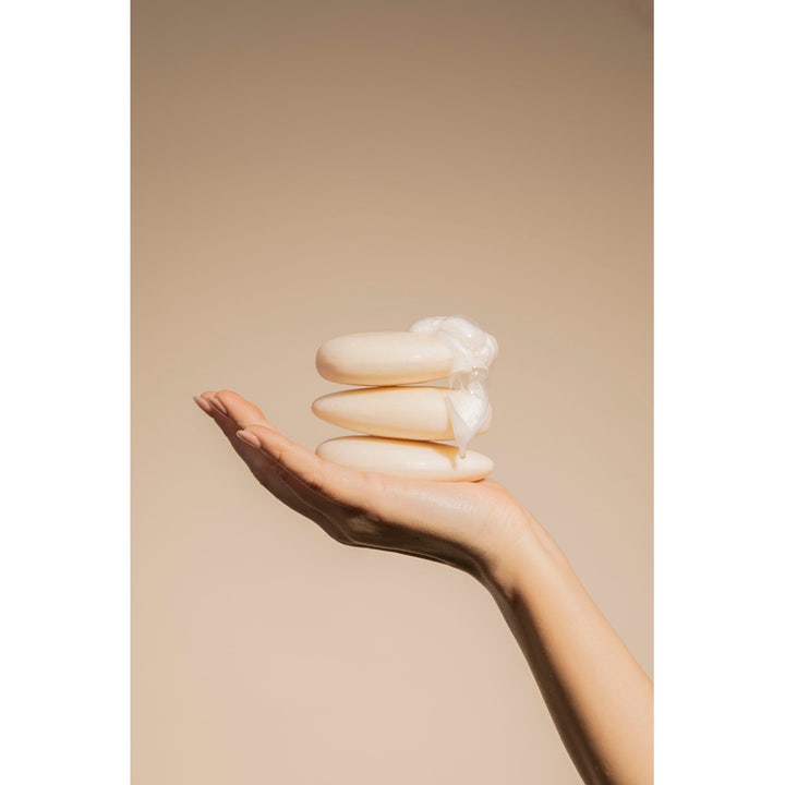 Compagnie de Provence Solid Face Cleanser 85 g fast ansiktsrens for sensitiv hud stablet i en hånd med kremet skum.