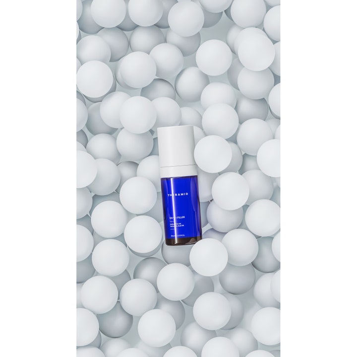 Niche Beauty Lab Theramid Hapca Filler 30 ml fuktighetsgivende serum i blå glassflaske liggende på hvite kuler