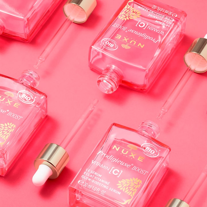 Nuxe Prodigieuse Boost Vitamin C Glow Boosting Serum 30 ml i rosa glassflasker med pipette på rosa bakgrunn