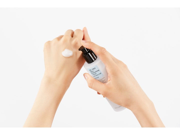 COSRX Oil Free Ultra Moisturizing Lotion 100 ml er en ansiktskrem som påføres håndryggen fra en hvit pumpeflaske.