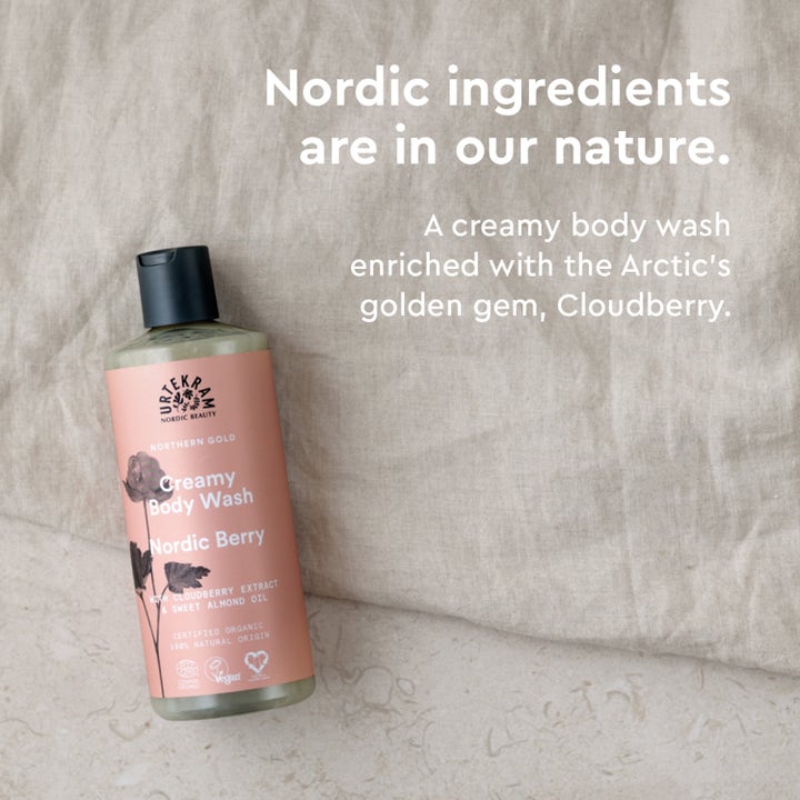 Urtekram Nordic Berry Creamy Body Wash 500 ml kremet dusjsåpe med molteekstrakt i ferskenfarget flaske på lyst stoff