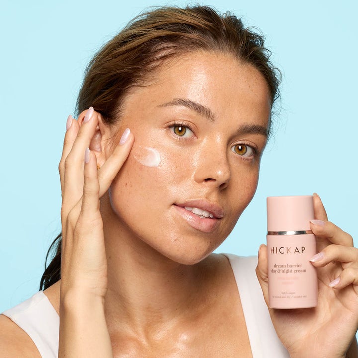 Hickap Dream Barrier Day & Night Cream 50 ml fuktighetskrem påføres på kinn ved siden av den rosa flasken.