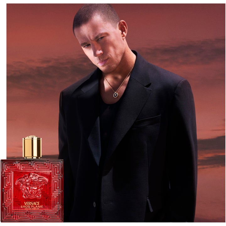 Versace Eros Flame 100 ml deospray med en mann i sort dress foran en rød solnedgang som skaper en maskulin følelse