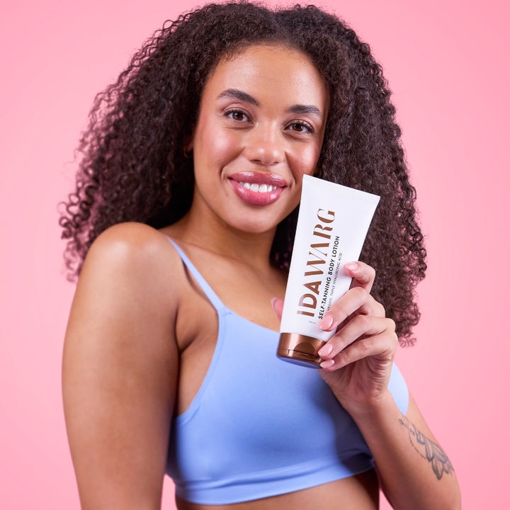 IDA WARG Beauty Self Tanning Body Lotion 200 ml gir glød holdt av kvinne mot rosa bakgrunn