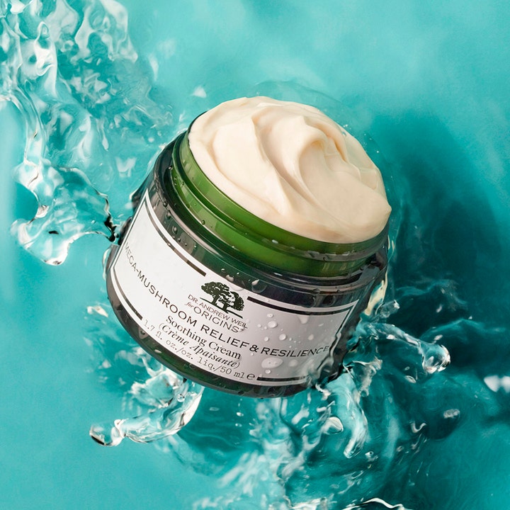 Origins Mega-Mushroom Skin Relief Face Cream 50 ml i grønn krukke omgitt av vannsprut