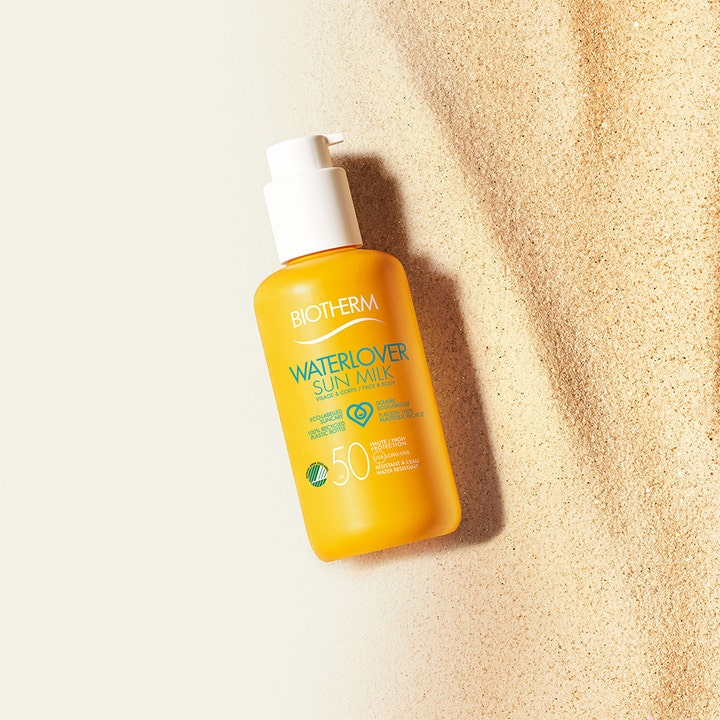 Biotherm Waterlover Sun Milk SPF50 200 ml fuktighetsgivende solkrem i gul pumpeflaske plassert på lys sand.