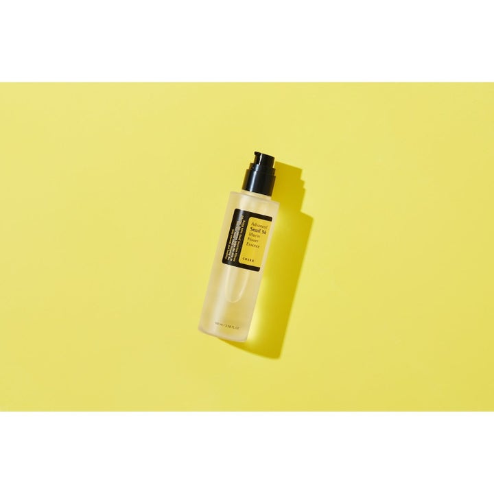 COSRX Advanced Snail 96 Essence 100 ml fuktighetsgivende ansiktsessens i pumpeflaske på gul bakgrunn