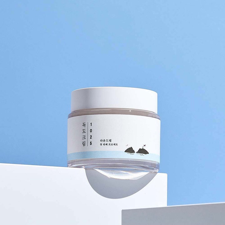 Round Lab 1025 Dokdo Cream 80 ml fuktighetsgivende ansiktskrem i hvit krukke mot en lys blå bakgrunn