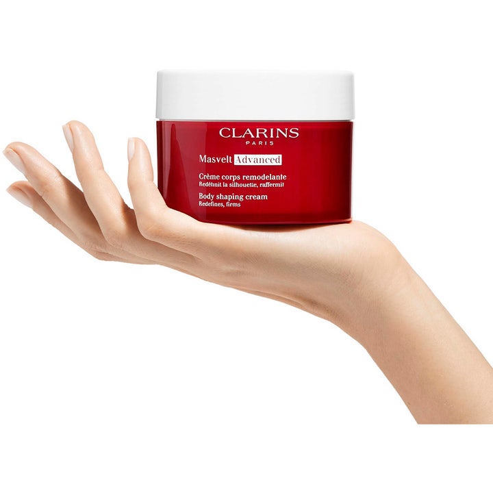 Clarins Masvelt Advanced Body Shaping Cream 200 ml oppstrammende kroppskrem i rød krukke med hvitt lokk i en hånd