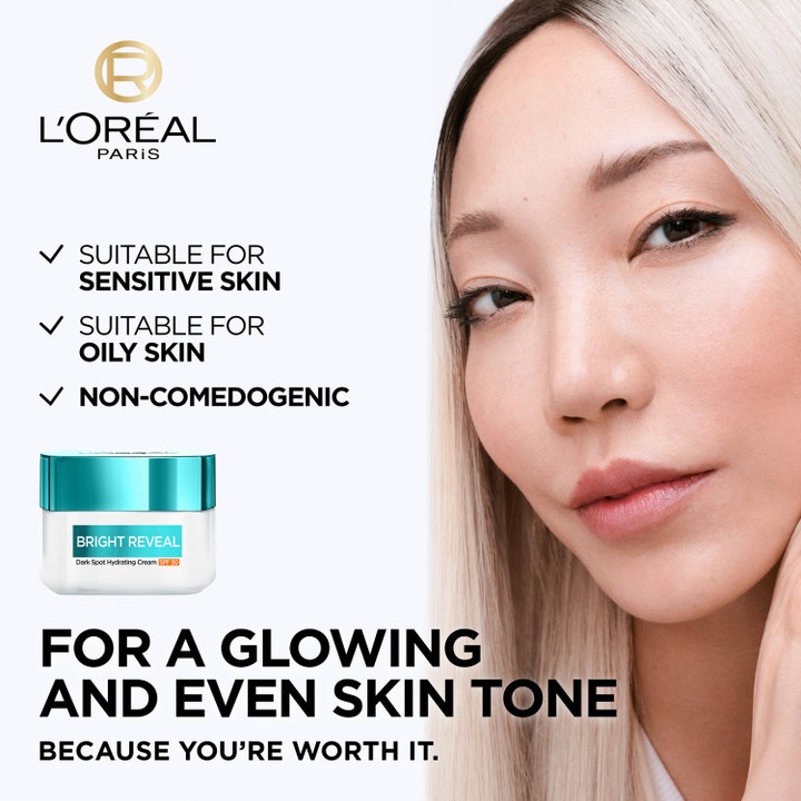 L'Oréal Paris Bright Reveal 50 ml fuktighetsgivende dagkrem i glasskrukke ved siden av kvinne med jevn hudtone