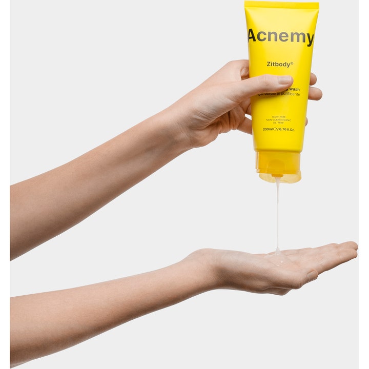 Niche Beauty Lab Acnemy Zitbody 200 ml rensende dusjsåpe i gul tube som klemmer ut klar gel i en håndflate