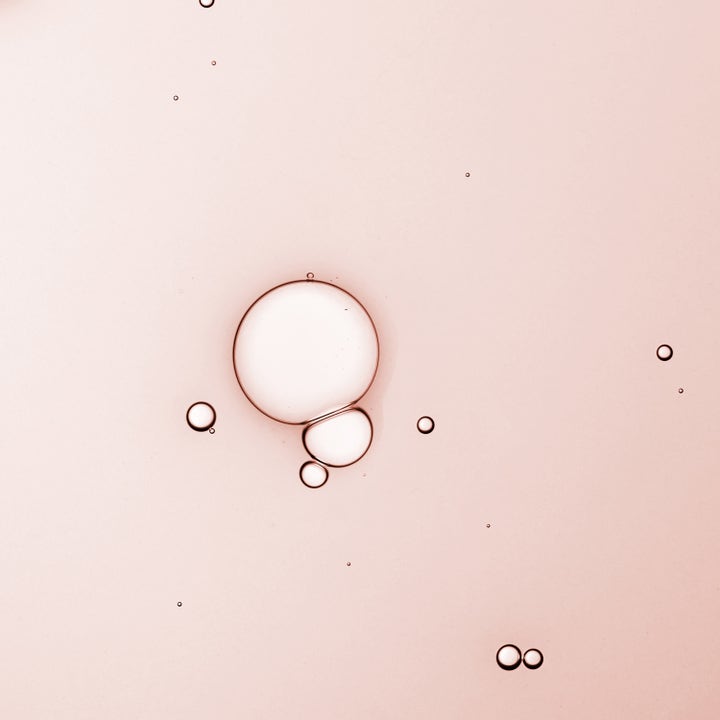 KORA Organics Turmeric Glow Drops 30 ml ansiktsserum har en lys rosa flytende tekstur med bobler som gir huden glød.