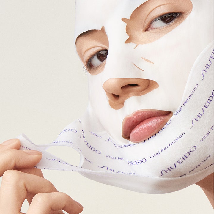Shiseido Vital Perfection Liftdefine Radiance Face Mask 10 g oppstrammende sheetmaske med hvit duk og blå logo på huden