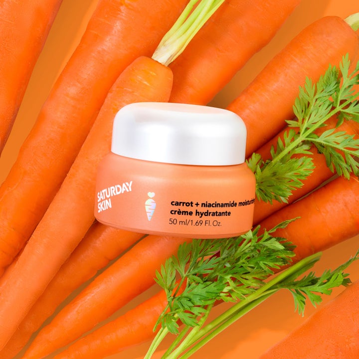 Saturday Skin Carrot + Niacinamide Moisturizing Cream 30 ml ansiktskrem i oransje krukke omgitt av ferske gulrøtter