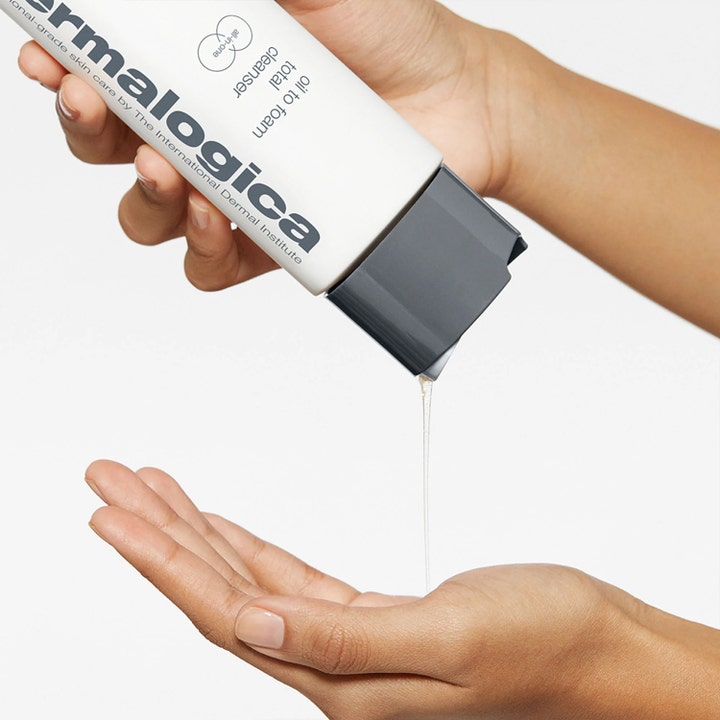Dermalogica Oil to Foam Cleanser 250 ml rengjøringsolje helles som en klar væske fra hvit flaske i en håndflate