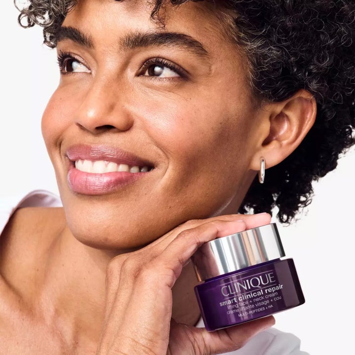 Clinique Smart Clinical Repair Lifting Face + Neck Cream 75 ml oppstrammende ansiktskrem i lilla krukke holdt av kvinne