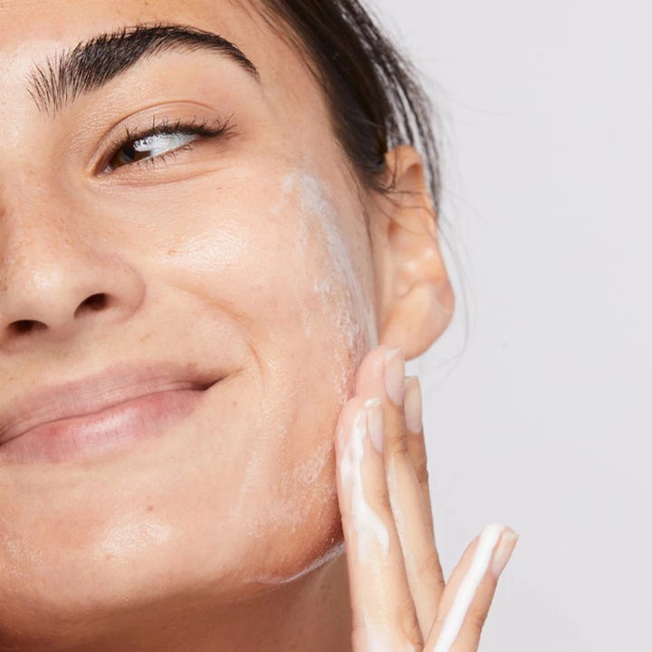 Dermalogica Clearing Skin Wash Duo 2 x 250 ml med salisylsyre viser en person som påfører hvitt skum på kinnet.