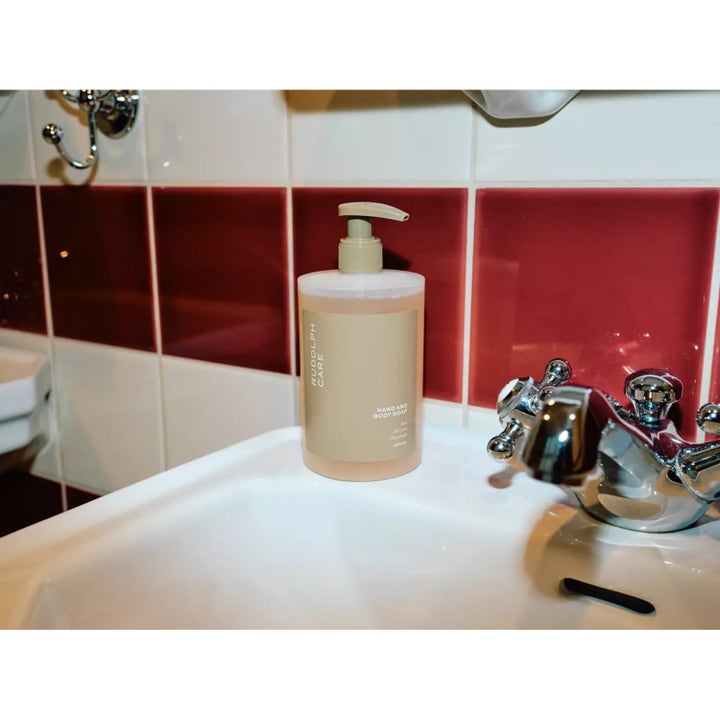 Rudolph Care Hand And Body Soap 500 ml pleiende dusjsåpe i beige pumpeflaske på en hvit servant