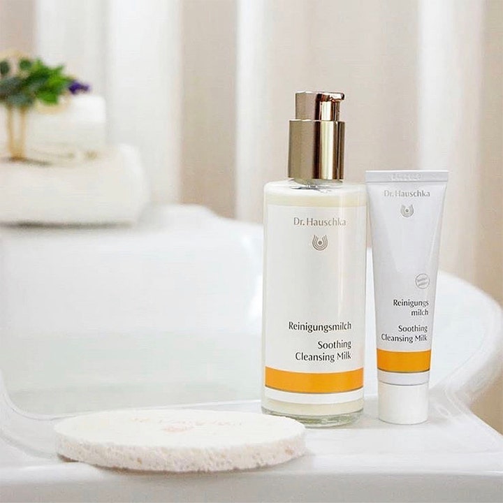 Dr. Hauschka Soothing Cleansing Milk 145 ml beroligende ansiktsrens i hvit glassflaske og tube i et lyst baderom.