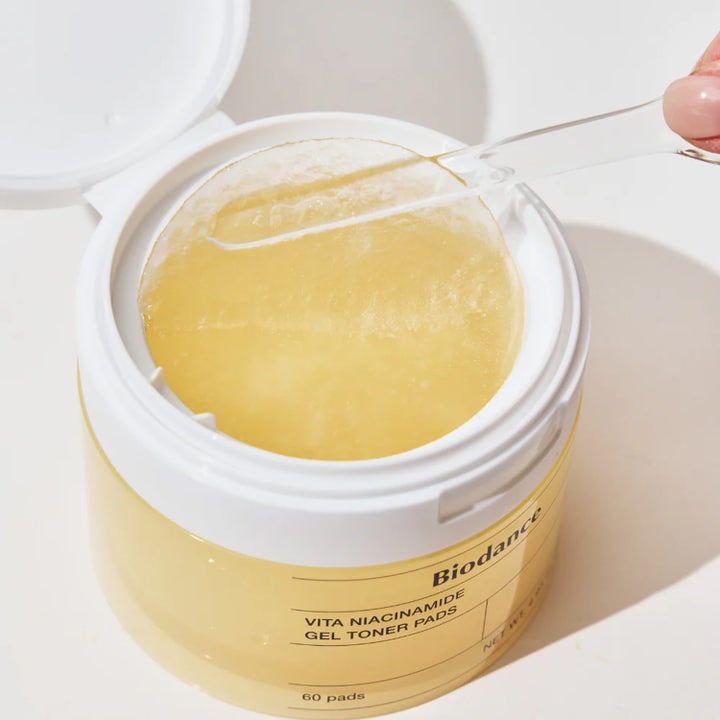 Biodance Vita Niacinamide Gel Toner Pads 60 stk gir glød med en tynn fuktig gelpad som løftes fra en gul krukke.