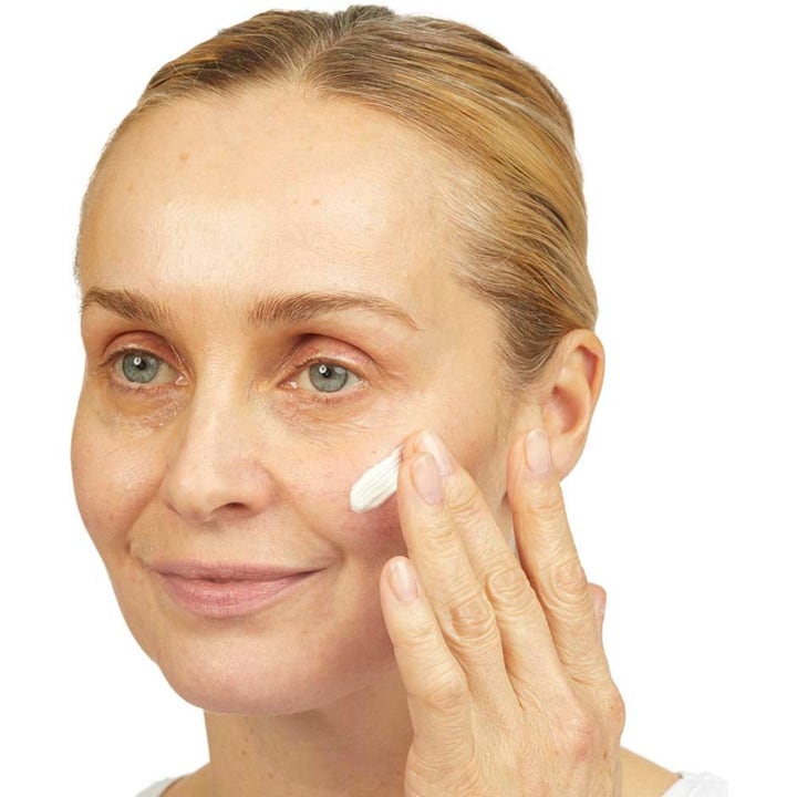 No7 Skincare Essential Set Lift & Luminate 80 ml hudpleie kvinne som påfører hvit ansiktskrem for økt glød