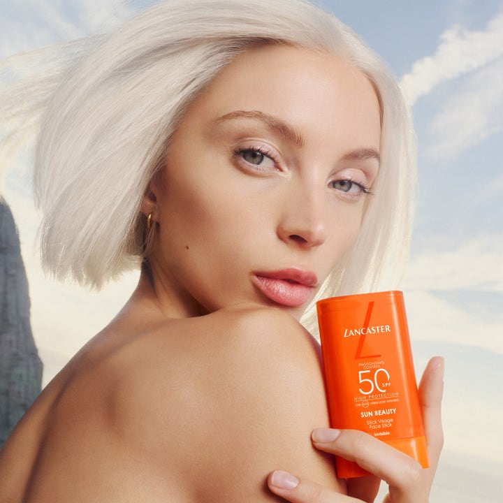 Lancaster Sun Beauty Face Stick SPF50 20 g solstift for ansiktet holdt av en lyshåret modell i sollys.