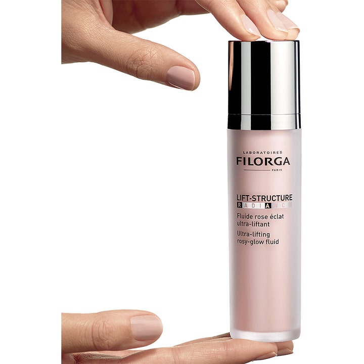 FILORGA Lift-Structure Radiance 50 ml glødgivende dagkrem i rosa frostet flaske med sølvlokk holdt av en hånd