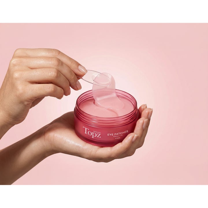Topz Daily Eye Patches 30 stk fuktighetsgivende øyemasker i rosa krukke som løftes med en spatel.