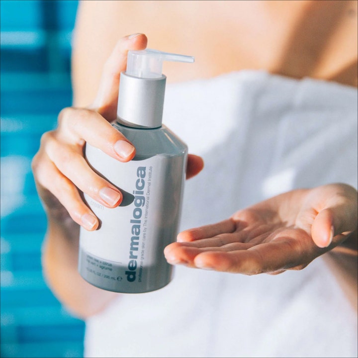 Dermalogica Body Hydrating Cream 295 ml fuktighetsgivende body lotion i grå pumpeflaske holdt av person i hvitt håndkle