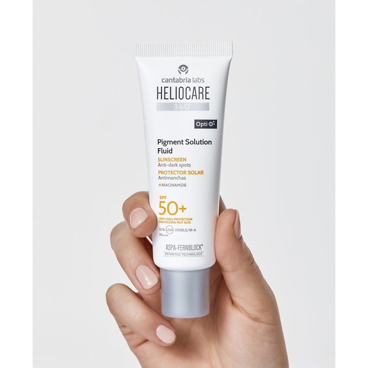 Heliocare Pigment Solution Fluid SPF 50+ 50 ml solkrem med niacinamid mot mørke flekker i hvit tube holdt i en hånd