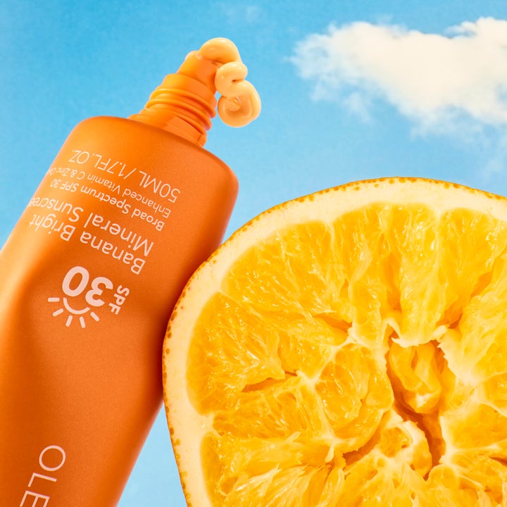 Ole Henriksen Truth Banana Bright Mineral Sunscreen SPF30 50 ml solkrem med gul tekstur ved en appelsin