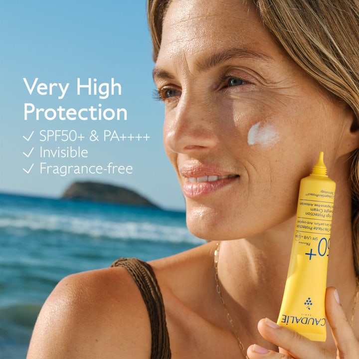 Caudalie Vinosun Lightweight Fluid 40 ml solkrem for ansiktet gir usynlig SPF50 beskyttelse vist med gul tube på stranden.