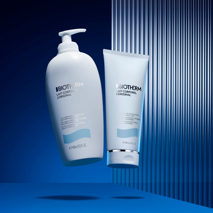 Biotherm Lait Corporel 200 ml fuktighetsgivende bodylotion i hvit tube ved siden av pumpeflaske mot blå bakgrunn.