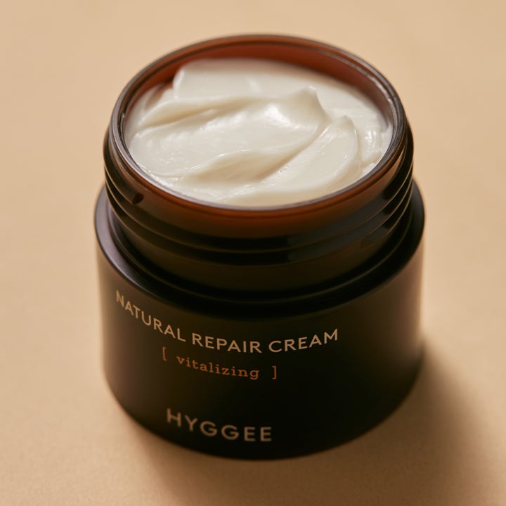 Hyggee Natural Repair Cream 50 ml vitaliserende ansiktskrem i åpen mørk krukke med fyldig hvit tekstur.
