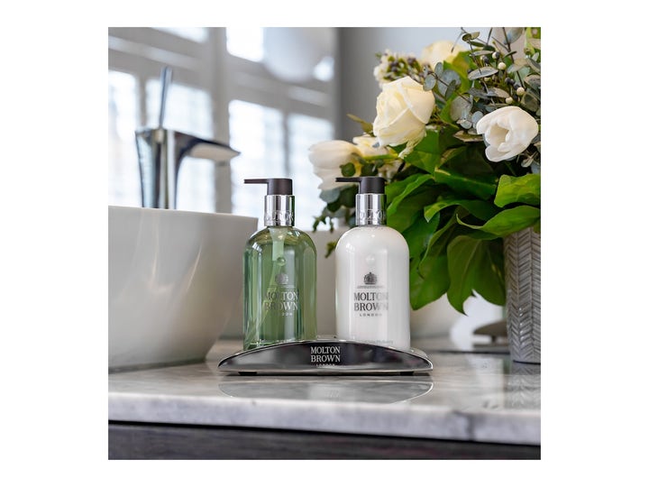 Molton Brown Refined White Mulberry Fine Liquid Hand Wash 300 ml håndsåpe i grønn flaske på sølvstativ i et lyst miljø.