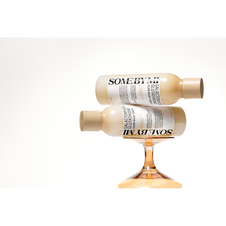 Some By Mi Galactomyces Glutathione Glow Milky Toner 200 ml glødgivende toner i beige flasker på en ravfarget glass-stett.