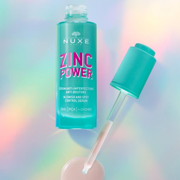 Nuxe Zinc Power Serum 30 ml mot urenheter i turkis glassflaske med pipette over en glitrende bakgrunn