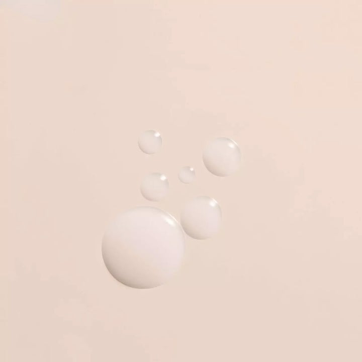 OPI Nature Strong Soften Up Pedi Soak 250 ml fotbad gir myk hud og viser flytende melkehvite dråper på lys bakgrunn