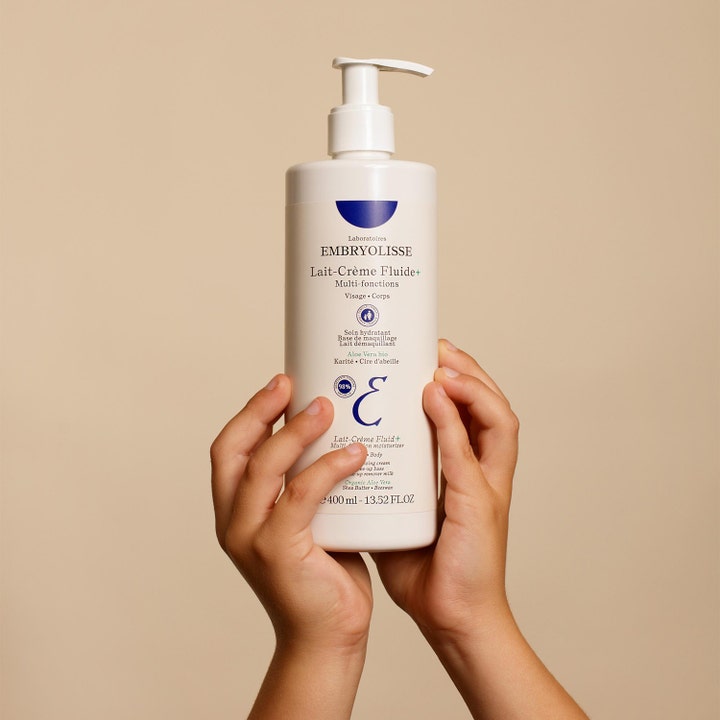 Embryolisse Lait-Crème Fluid+ 400 ml fuktighetskrem i hvit pumpeflaske som holdes av to barnehender.