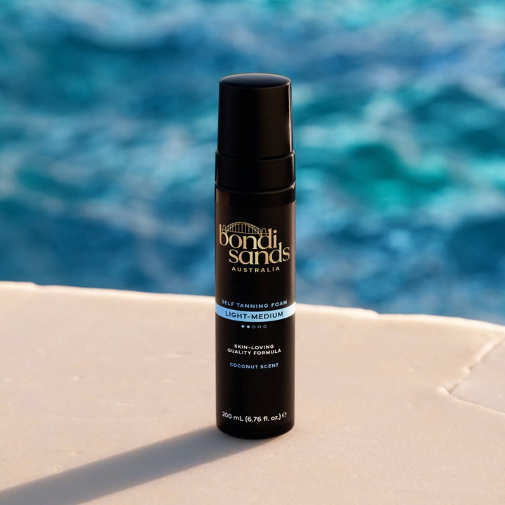 Bondi Sands Self Tanning Foam Light Medium 200 ml selvbruning i svart flaske ved et solfylt blått basseng