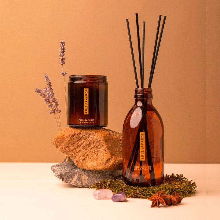 Compagnie de Provence Anise Lavender 495 ml handtvål i ravgule glasskrukker omgitt av lavendel, mose og stjerneanis.
