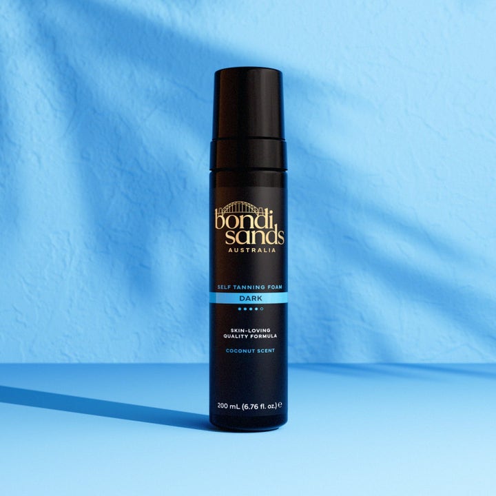 Bondi Sands Self Tanning Foam Dark 200 ml selvbruning i svart pumpeflaske som gir dyp farge mot blå bakgrunn.