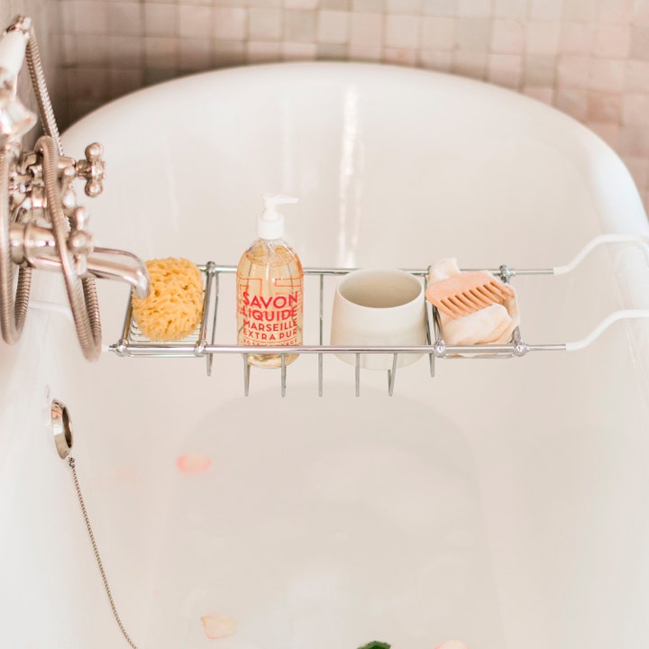 Compagnie de Provence Liquid Marseille Soap Wild Rose 495 ml flytende håndsåpe i en badekarkurv med svamp og kam.