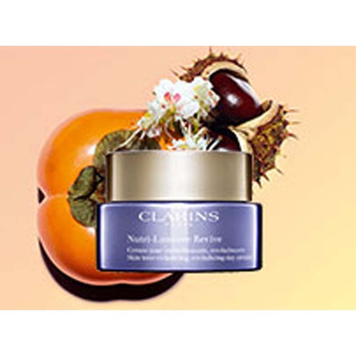 Clarins Nutri-Lumière Revive 50 ml dagkrem som gir glød i lilla krukke med gullokk vist med kakiplomme og kastanje.