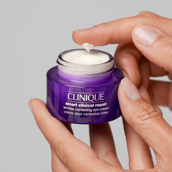 Clinique Smart Clinical Repair Wrinkle Eye Cream 30 ml øyekrem i lilla krukke med hvit tekstur på en finger.