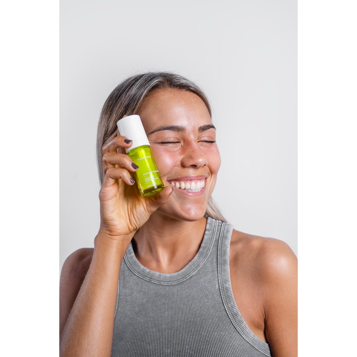 Niche Beauty Lab Theramid Smoothing Treatment 30 ml serum holdes av en smilende kvinne mot ansiktet.
